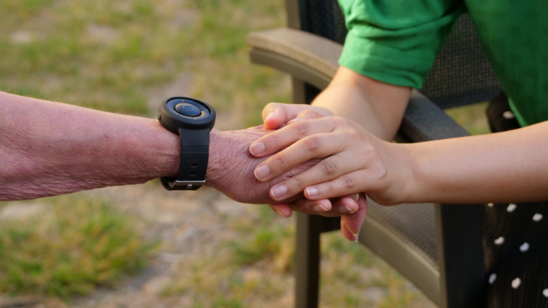Äldre person som använder MiniFinder Nano trygghetslarm.