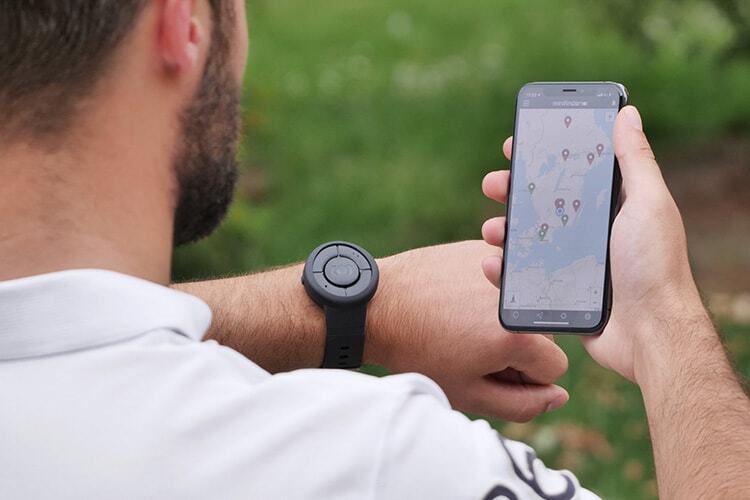 Person wearing a personal safety alarm watch while viewing location tracking on a smartphone