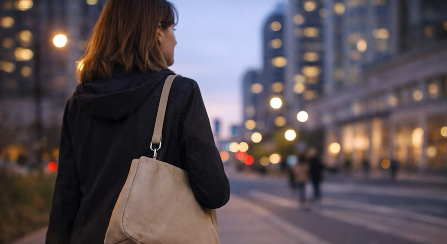 Eine Frau geht spät am Abend nach Hause und trägt einen Überfallalarm sicher in ihrer Tasche.
