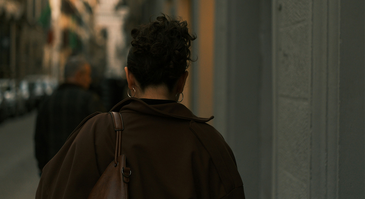 Woman walking alone on a city street, seen from behind, illustrating the need for personal safety.
