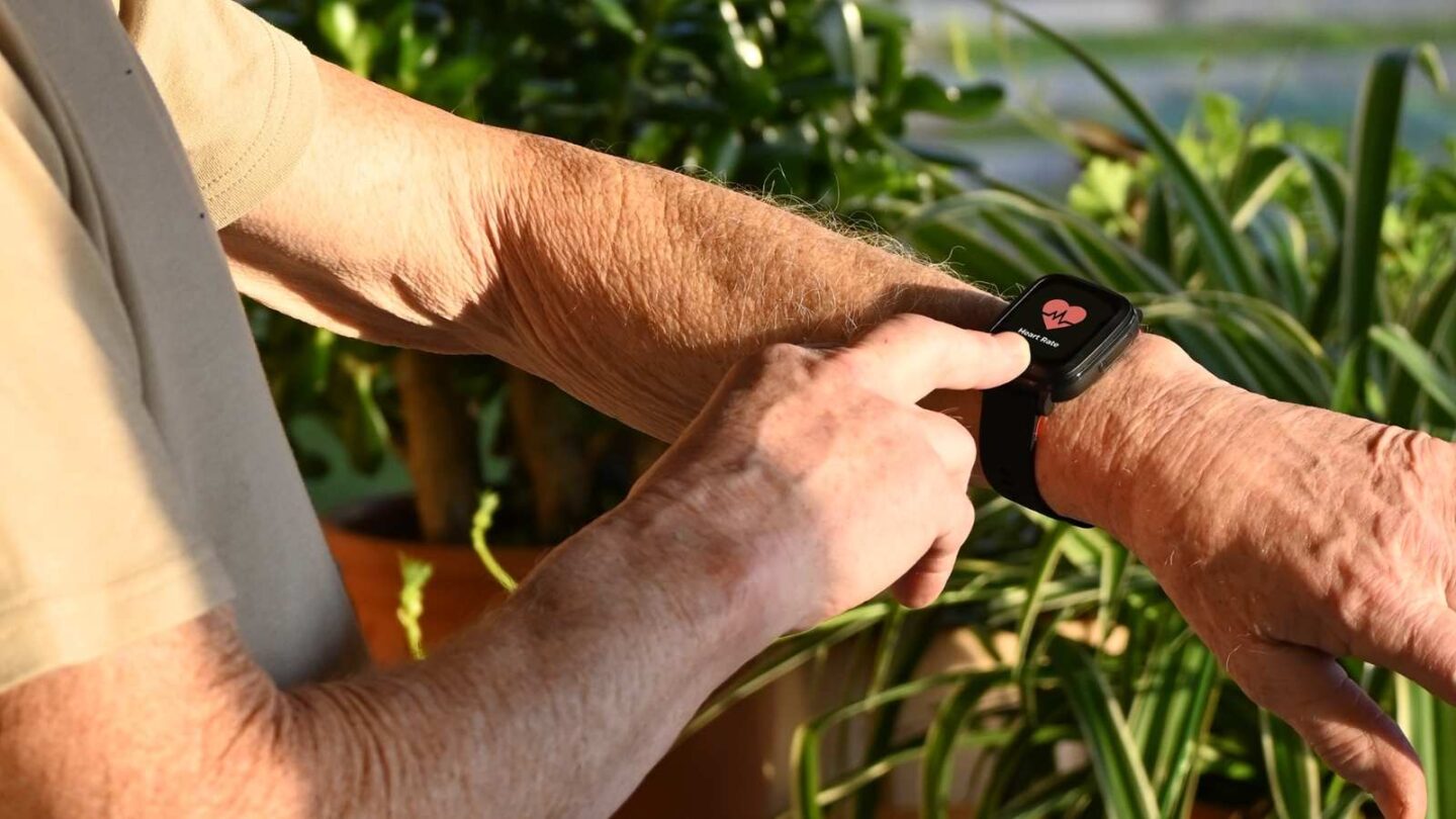 Senior wearing a GPS watch abroad with palm trees in the background.