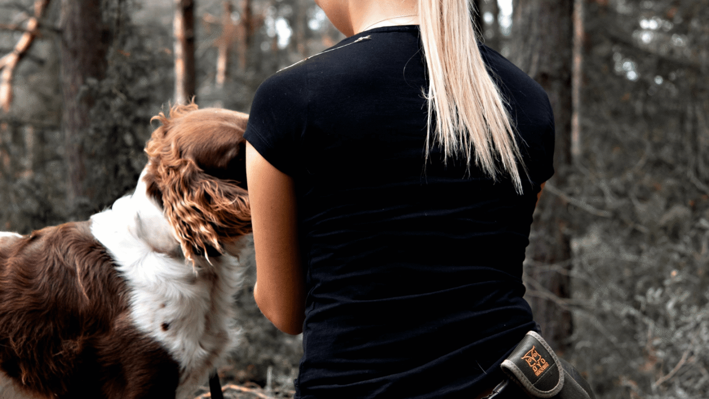 Dog owner kneeling down and calling her dog, which happily returns for comfort and reassurance after being reunited.
