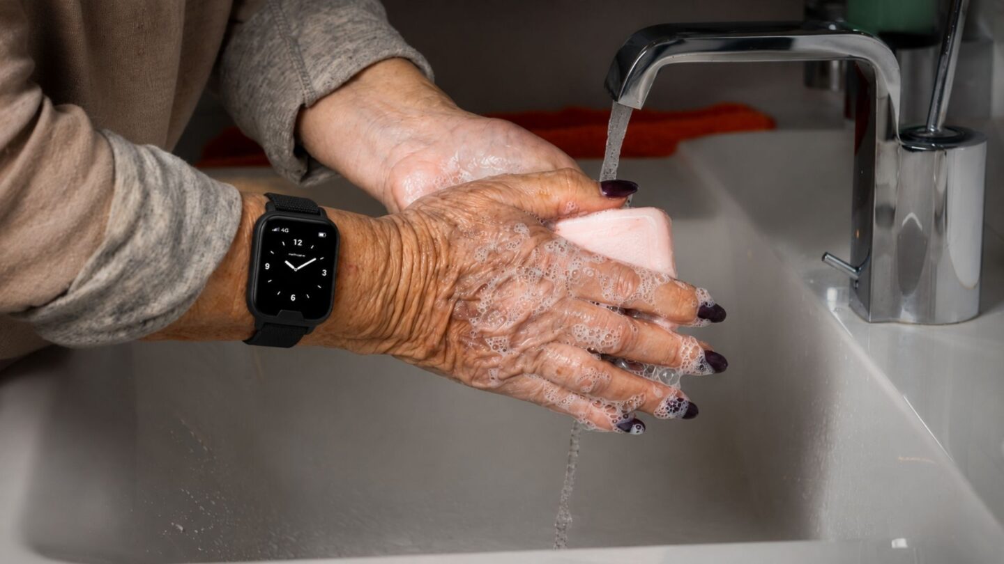Senior wearing a water-resistant safety watch while washing hands