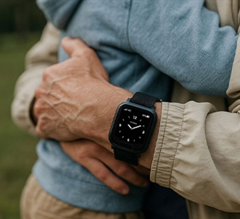 Older adult hugging a child while wearing a personal alarm watch on their wrist.