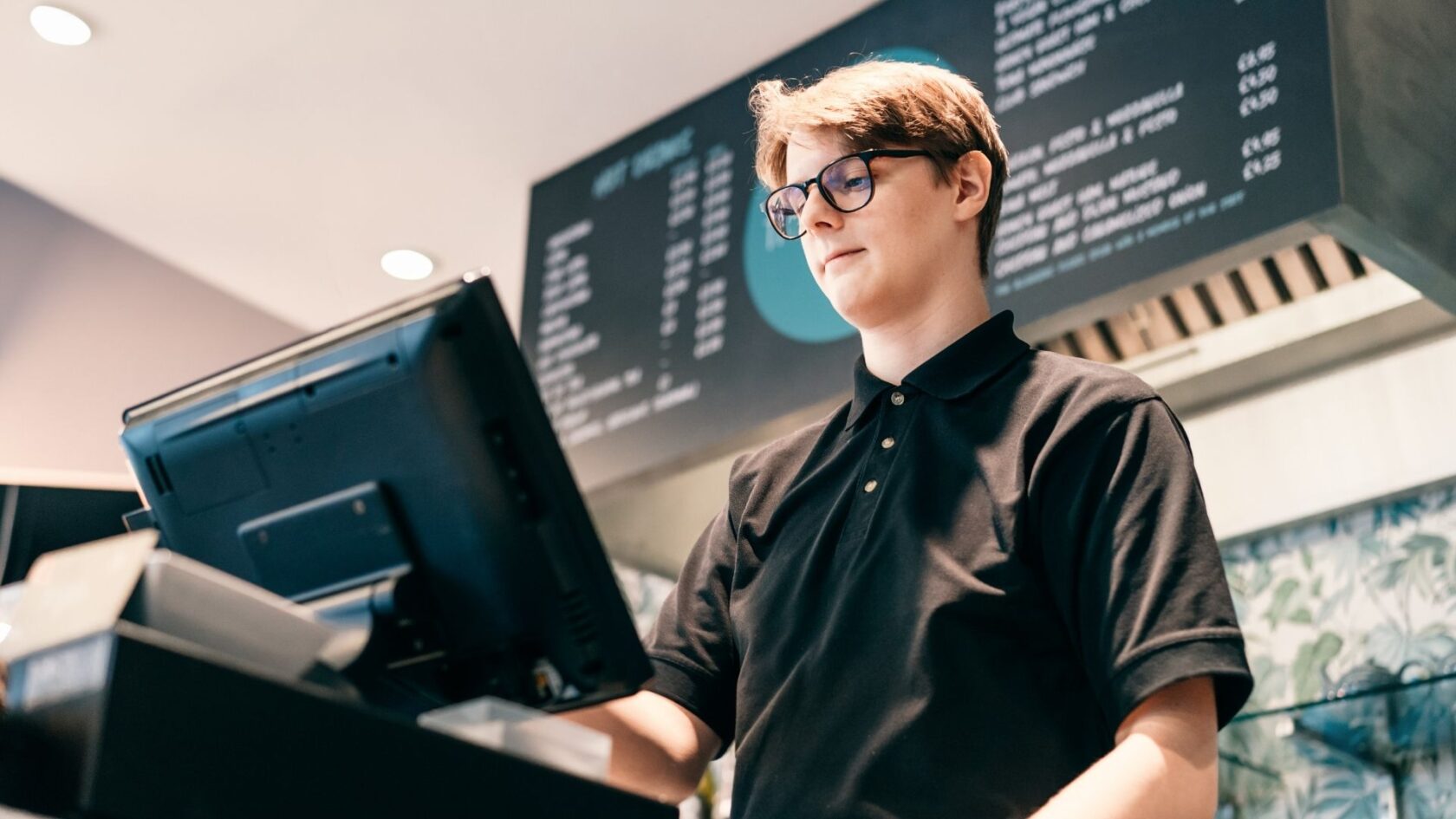 Retail employee working at a shop checkout where a panic alarm can help improve workplace safety.